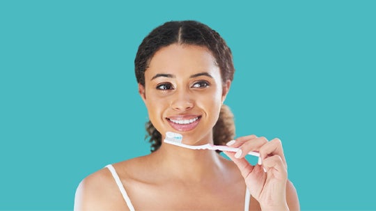 Žena se širokým úsměvem ukazuje zdravé zuby.